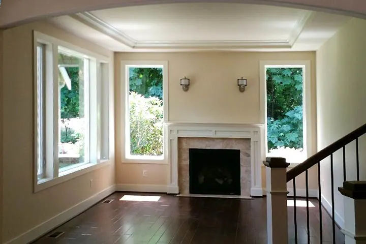 Finished living room with tall white Prime vinyl windows flanking a fireplace
